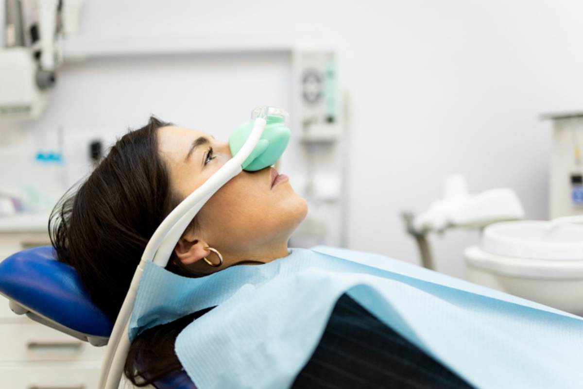 An adult woman sits in a dentist's office wearing a nasal mask to inhale nitrous oxide. Dentist fear concept. Feeling of relaxation with laughing gas.